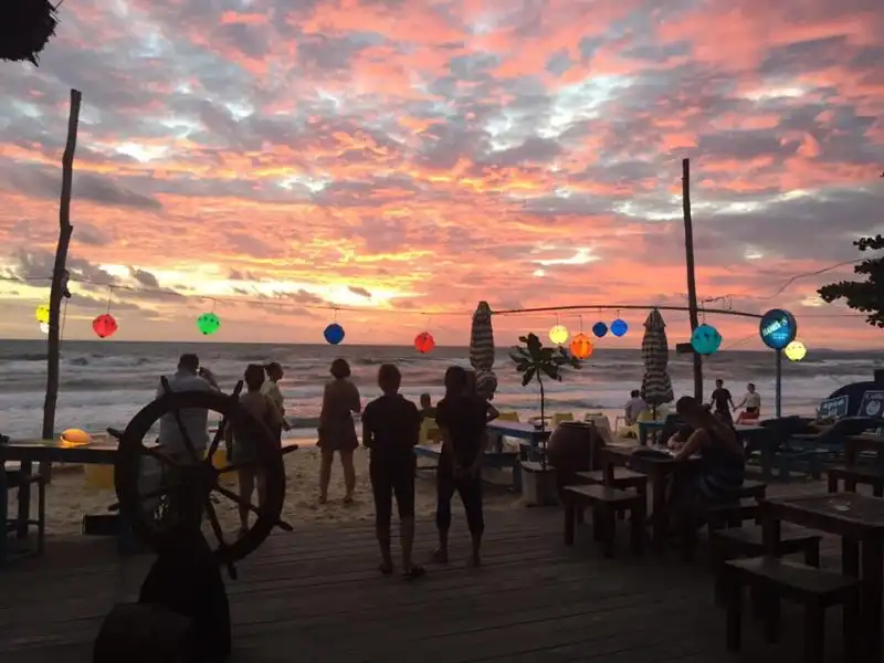 Полный Путеводитель по Сансет Таун Фукуок: Что Посмотреть и Чем Заняться. 15 Туристы гуляют по набережной Сансет Таун Фукуок среди красочных зданий.